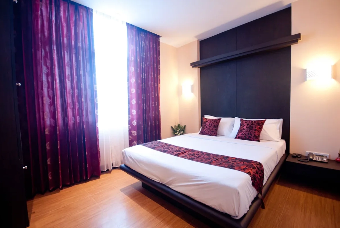 Deluxe room interior showing bed and window natural light ภายในห้องดลักซ์ เห็นเตียงนอนและแสงธรรมชาติจากหน้าต่าง