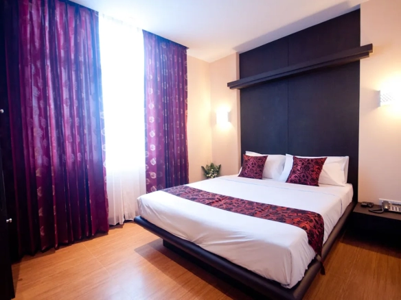 Deluxe room interior showing bed and window natural light ภายในห้องดลักซ์ เห็นเตียงนอนและแสงธรรมชาติจากหน้าต่าง