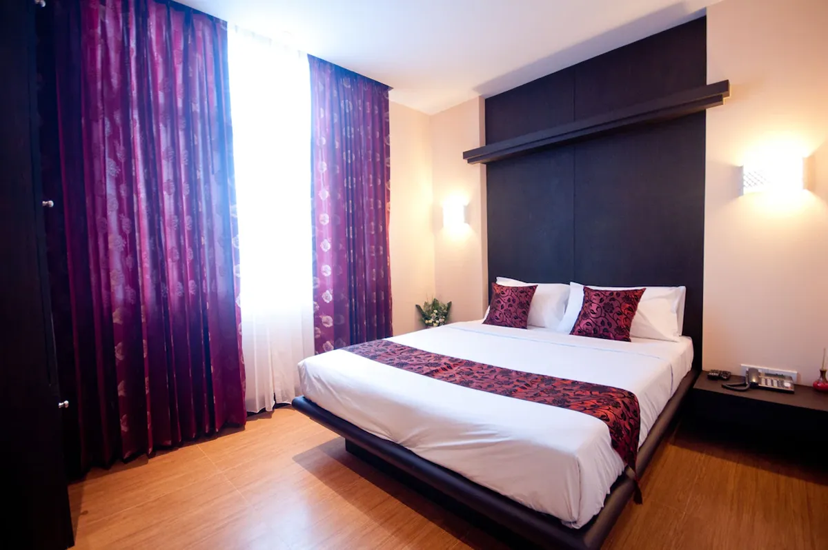 Deluxe room interior showing bed and window natural light ภายในห้องดลักซ์ เห็นเตียงนอนและแสงธรรมชาติจากหน้าต่าง