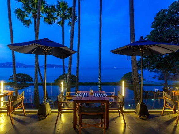 Poolside dining with sea view at night in a luxury beachfront resort