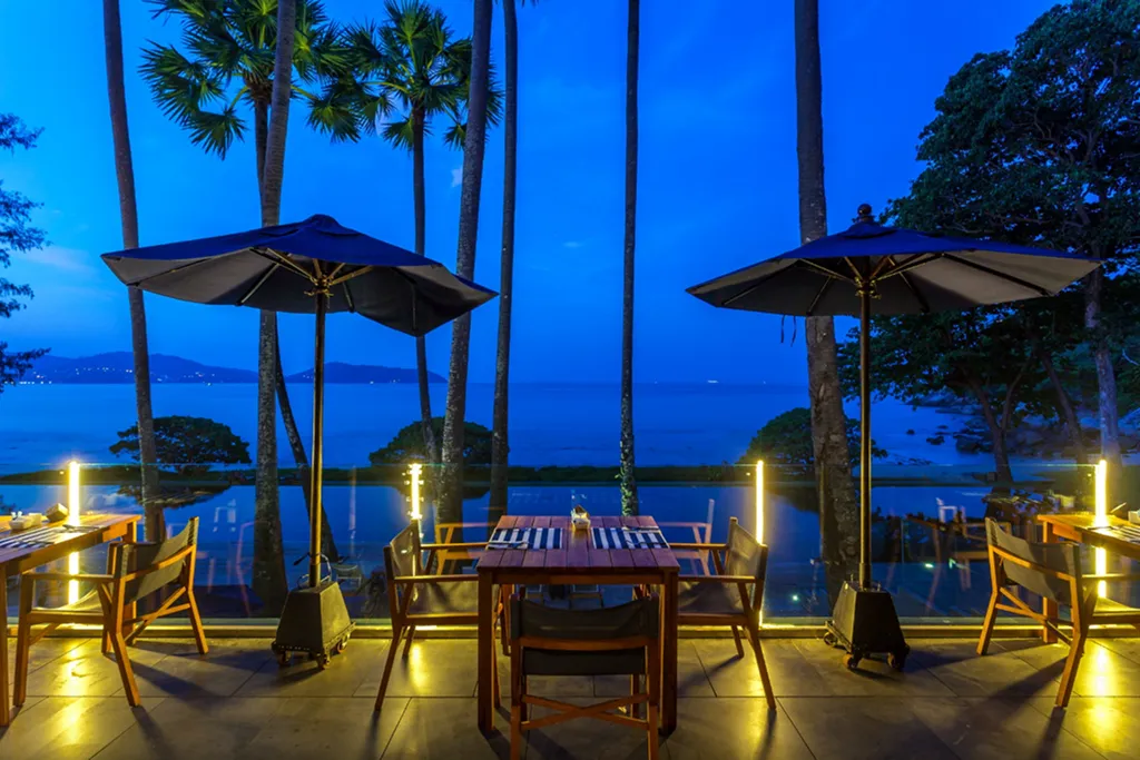 Poolside dining with sea view at night in a luxury beachfront resort