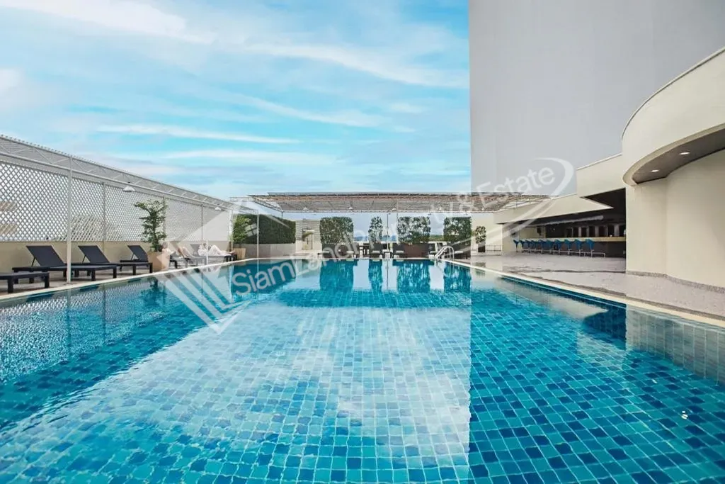 Beautiful outdoor swimming pool area reflecting the clear blue sky and modern hotel architecture