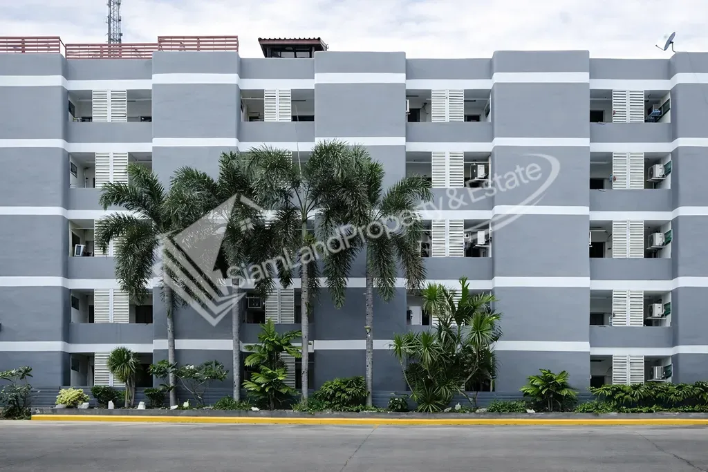 Modern grey apartment building facade decorated with green tropical palm trees