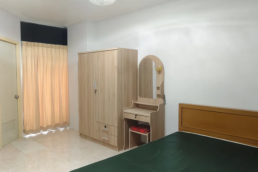 Furnished studio apartment bedroom featuring a wooden wardrobe and dressing table setup